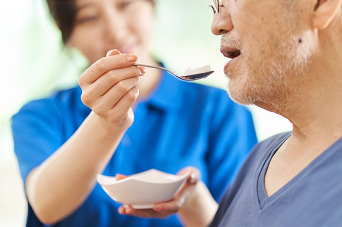 Nurse feeding elder man